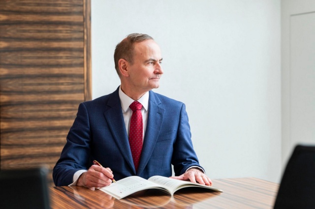 Chief Investment Officer Dr. Christoph Kind sitzt mit einer Publikation am Konferenztisch.